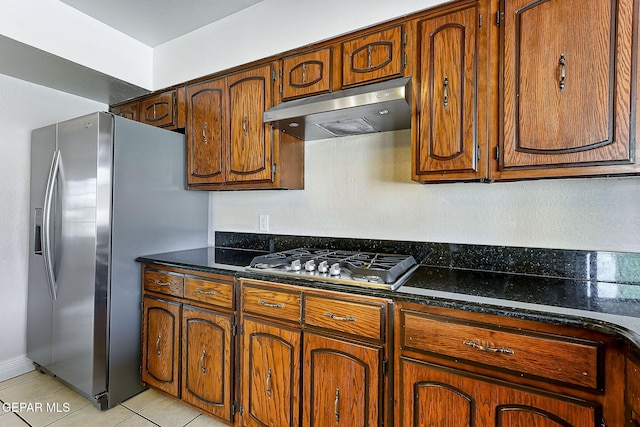 kitchen with dark stone countertops, light tile patterned floors, and stainless steel appliances