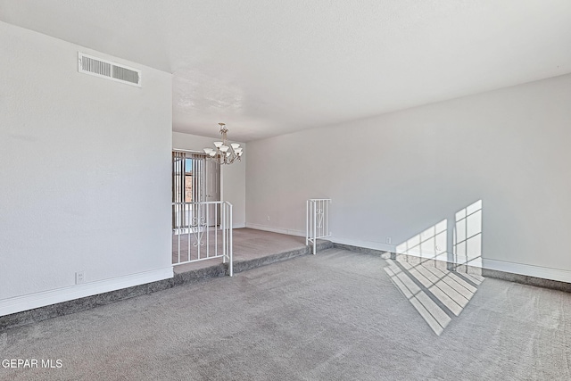 carpeted empty room with an inviting chandelier