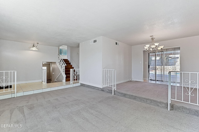 carpeted spare room with an inviting chandelier