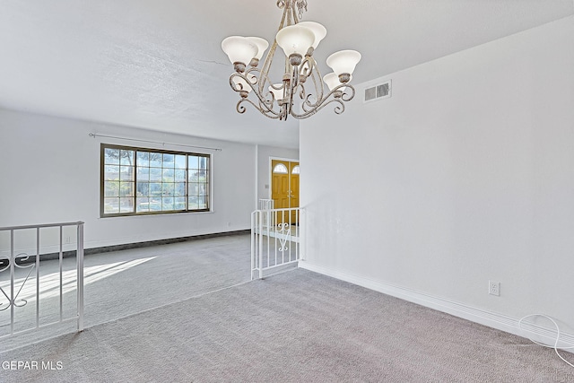 unfurnished room featuring carpet floors and an inviting chandelier