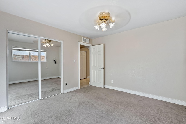 unfurnished bedroom with ceiling fan with notable chandelier, light colored carpet, and a closet