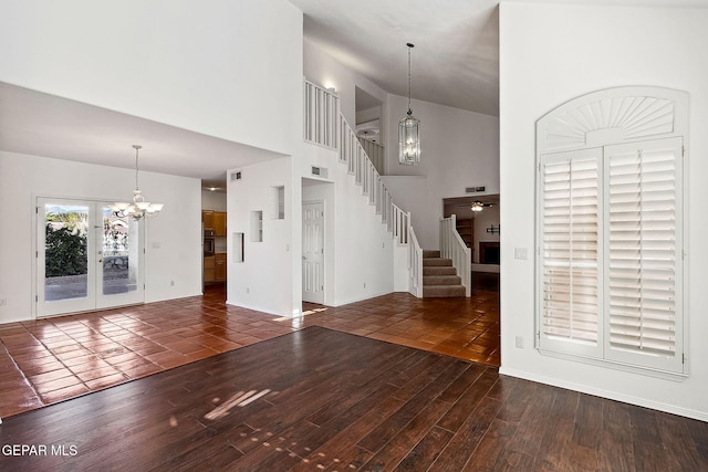 unfurnished living room with a towering ceiling, french doors, ceiling fan with notable chandelier, and dark hardwood / wood-style floors