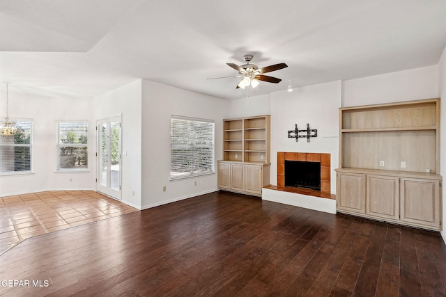 unfurnished living room with a fireplace, ceiling fan, and dark wood-type flooring