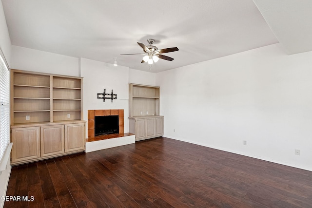 unfurnished living room featuring a tiled fireplace, ceiling fan, and dark hardwood / wood-style flooring