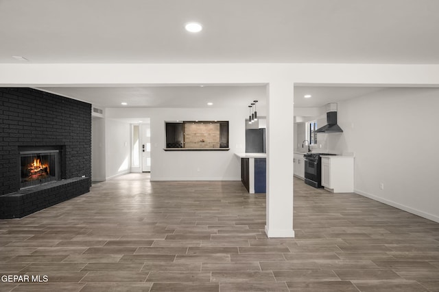 unfurnished living room with a barn door, visible vents, wood tiled floor, a fireplace, and recessed lighting