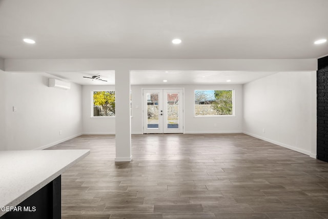 unfurnished living room with baseboards, a wall unit AC, wood finished floors, and recessed lighting