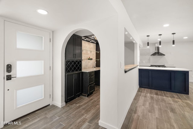 interior space with wall chimney range hood, wood tiled floor, stainless steel gas stovetop, and recessed lighting