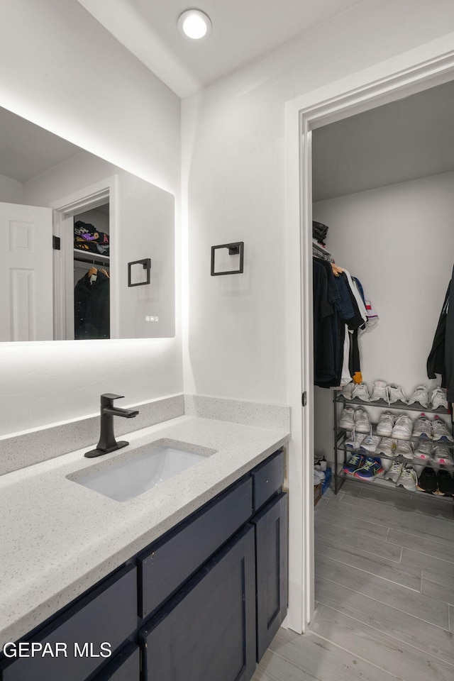 bathroom with a spacious closet, wood finished floors, and vanity