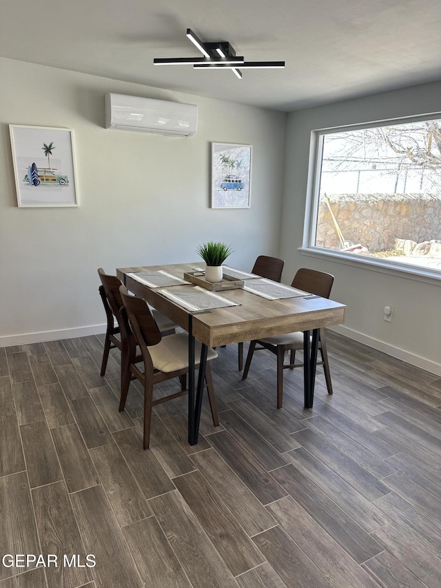 dining area with wood finish floors, an AC wall unit, and baseboards