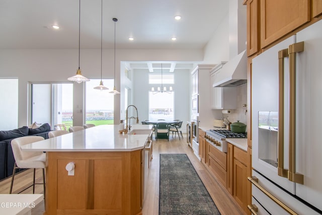 kitchen featuring a kitchen breakfast bar, a spacious island, decorative light fixtures, light hardwood / wood-style floors, and high quality fridge