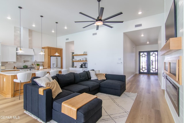 living room featuring ceiling fan, french doors, and light hardwood / wood-style flooring