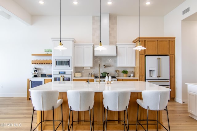 kitchen with decorative backsplash, white cabinets, an island with sink, and white appliances