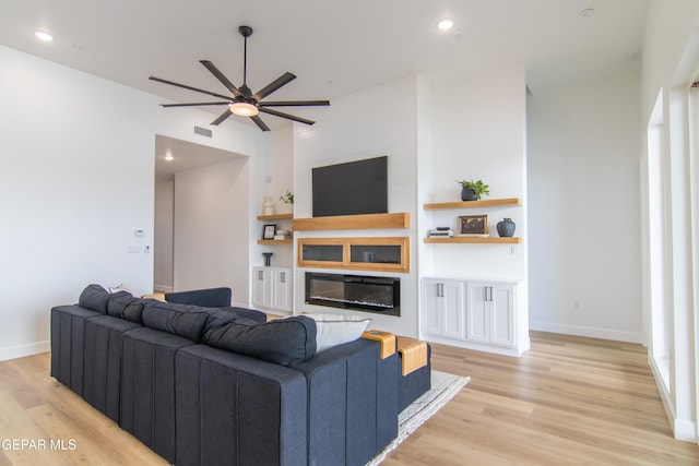 living room with a fireplace, ceiling fan, light hardwood / wood-style flooring, and lofted ceiling