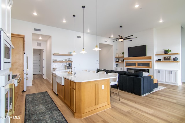 kitchen with a kitchen island with sink, sink, hanging light fixtures, stainless steel dishwasher, and ceiling fan