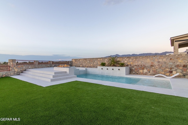 pool at dusk with a lawn and pool water feature