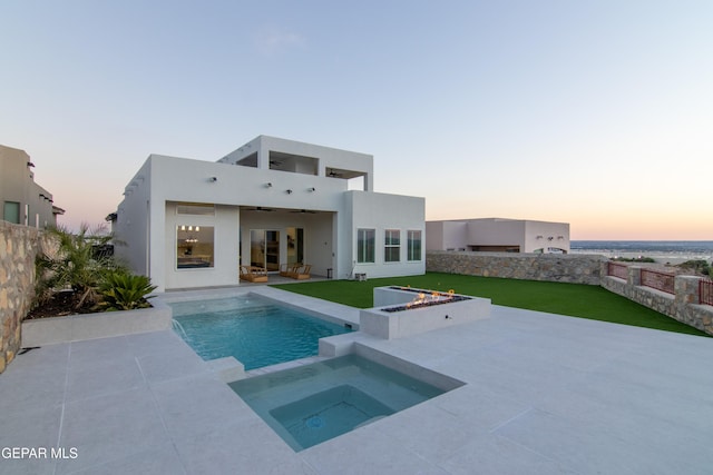 back house at dusk with an outdoor living space with a fire pit, ceiling fan, a patio, and a pool with hot tub