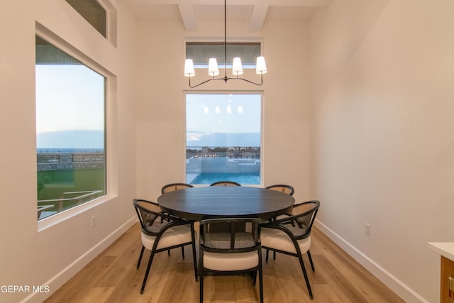 dining area featuring beamed ceiling, light hardwood / wood-style floors, and a chandelier