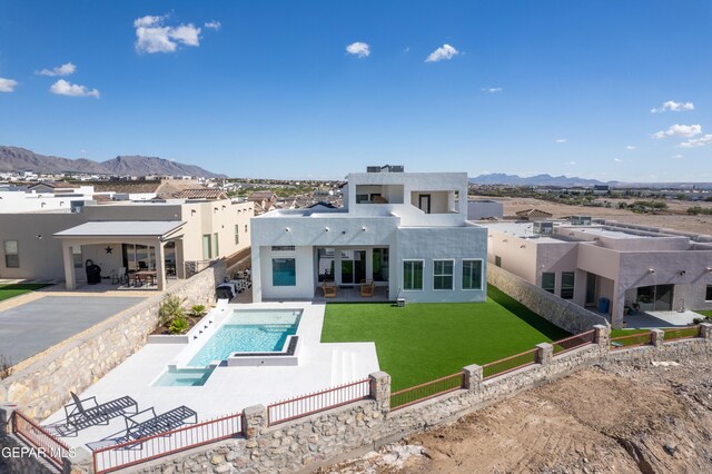 rear view of house with a mountain view, a yard, and a patio area