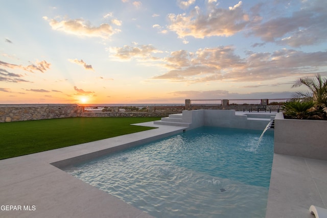 pool at dusk with a yard and pool water feature