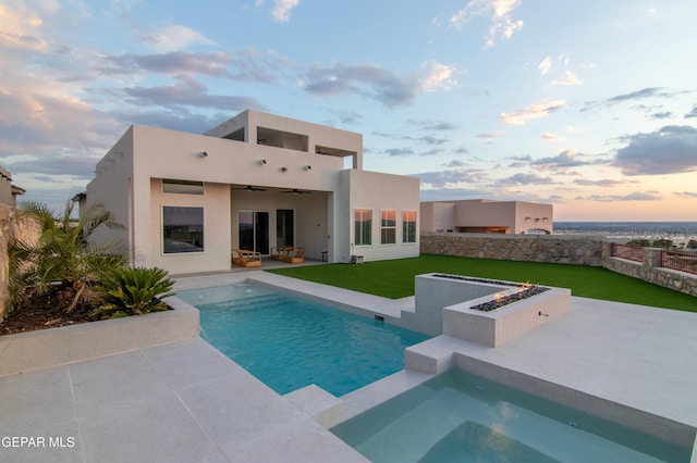 back house at dusk featuring a pool with hot tub, an outdoor living space, ceiling fan, a patio area, and a lawn