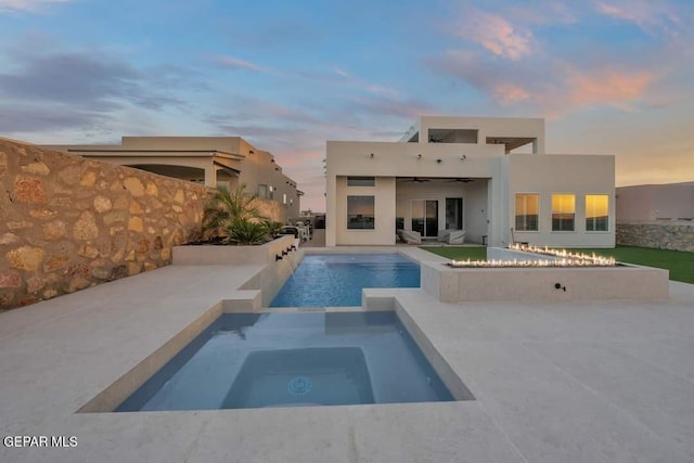 pool at dusk featuring an in ground hot tub, a patio, and ceiling fan