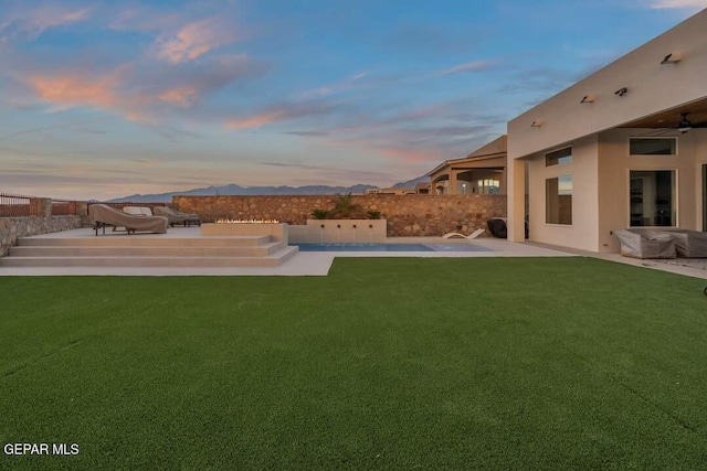 yard at dusk with a mountain view and a patio