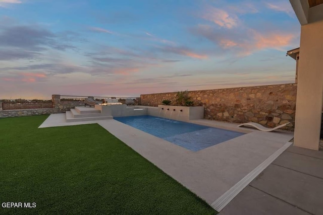 pool at dusk featuring a patio area and a yard