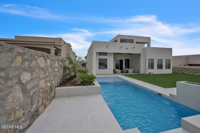 rear view of house featuring a lawn, ceiling fan, and a fenced in pool