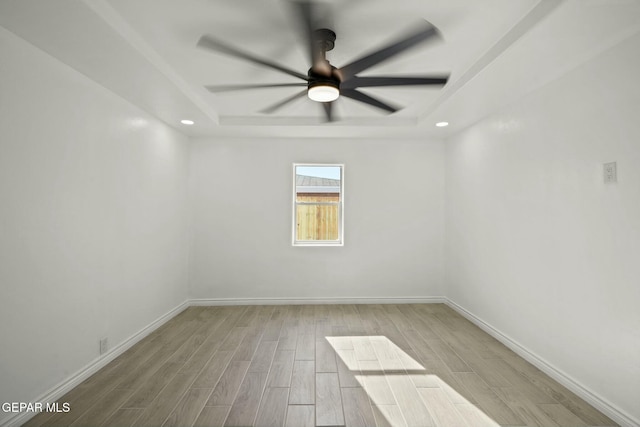 empty room featuring a tray ceiling and ceiling fan