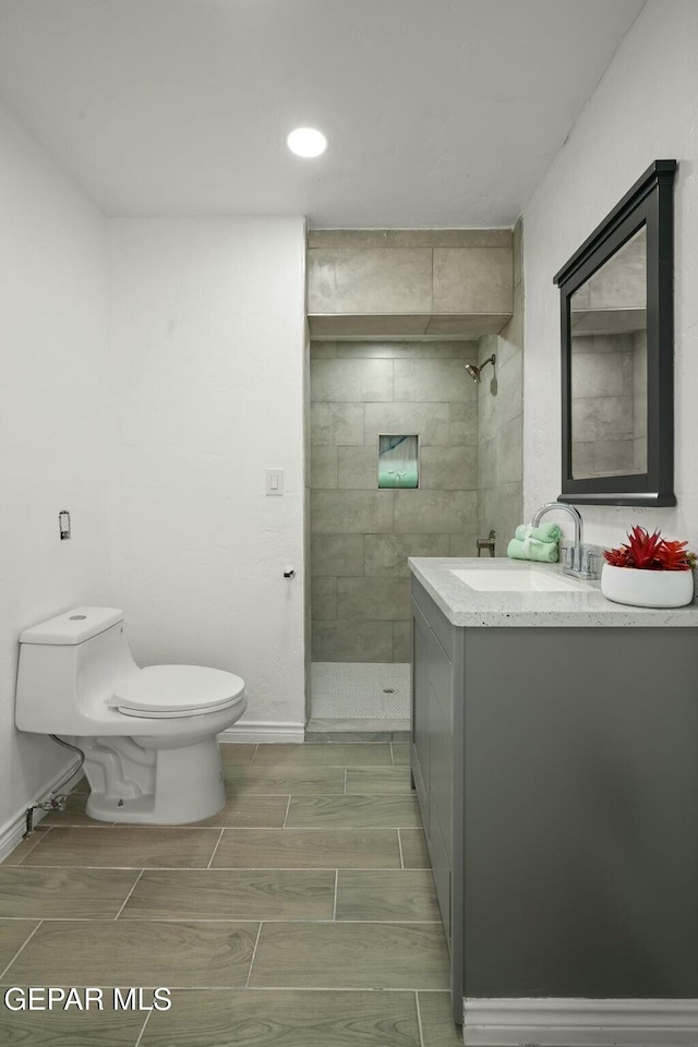 bathroom featuring tiled shower, vanity, and toilet