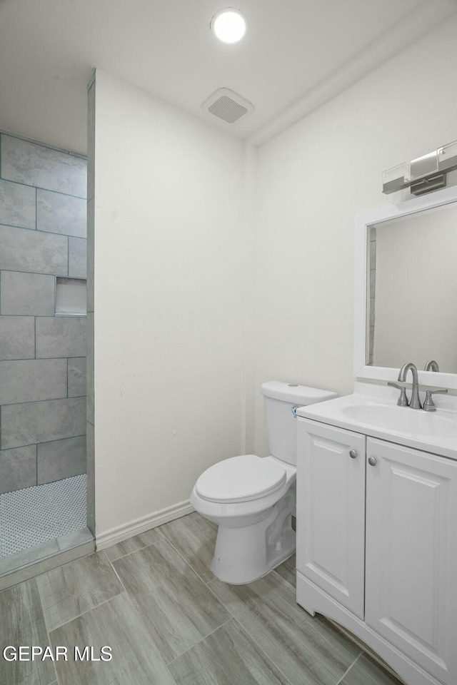 bathroom with vanity, toilet, and a tile shower