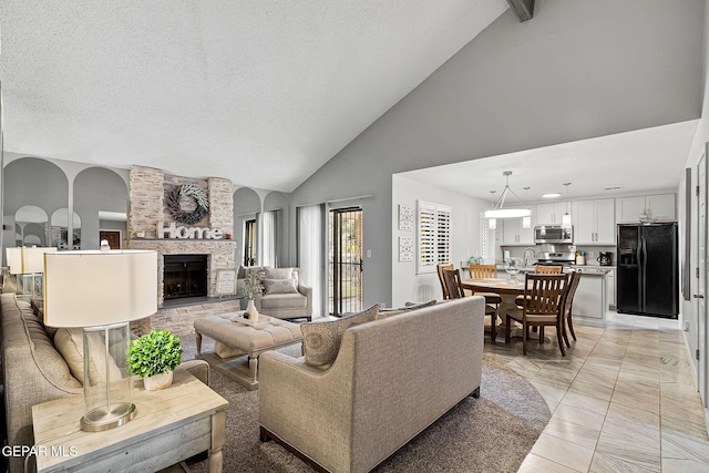 living room with high vaulted ceiling, a stone fireplace, light tile patterned floors, a textured ceiling, and beamed ceiling