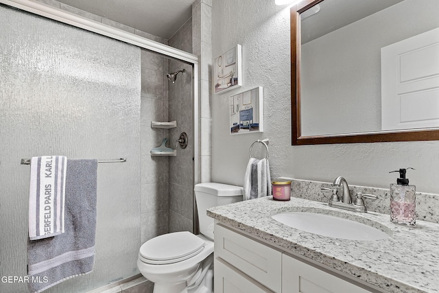 bathroom with vanity, a shower with shower door, and toilet