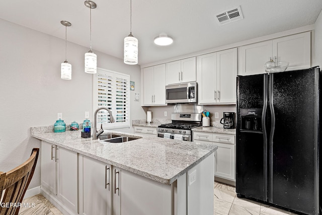 kitchen featuring kitchen peninsula, light stone counters, stainless steel appliances, sink, and white cabinetry