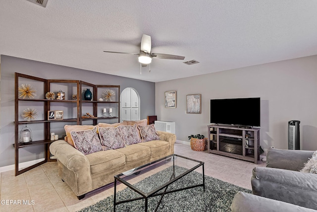 living room featuring ceiling fan, light tile patterned flooring, and a textured ceiling