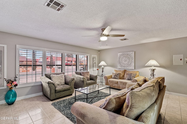 living room with ceiling fan, light tile patterned flooring, and a textured ceiling