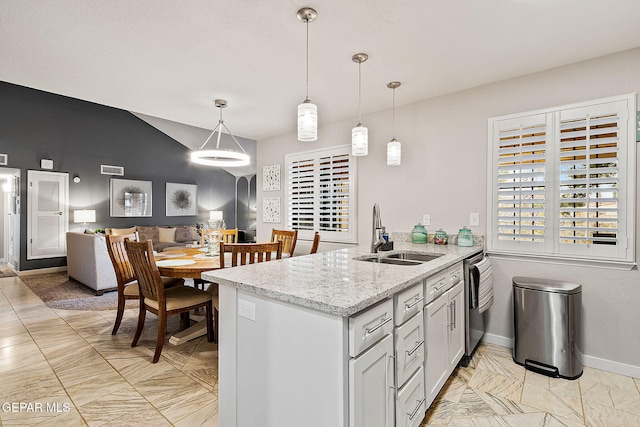 kitchen featuring kitchen peninsula, light stone countertops, stainless steel dishwasher, sink, and pendant lighting