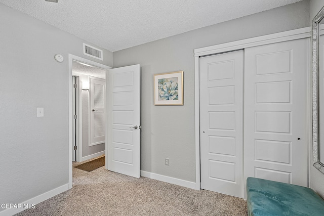 unfurnished bedroom with light carpet, a textured ceiling, and a closet