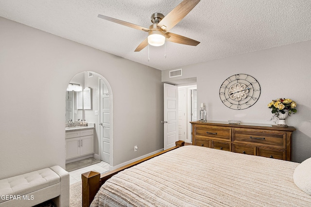 bedroom with a textured ceiling, ensuite bath, and ceiling fan