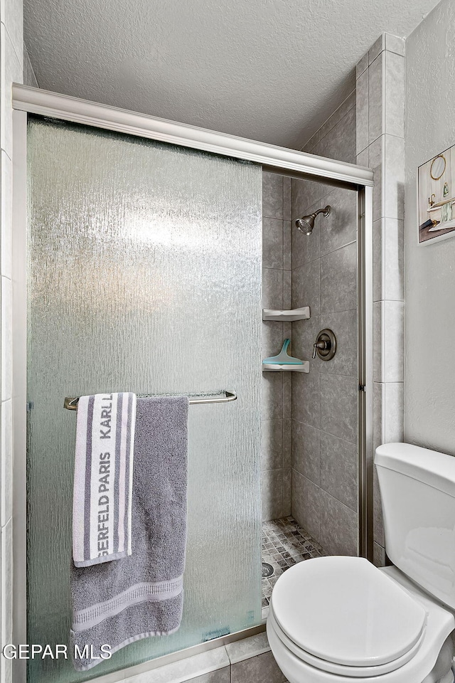 bathroom with tile patterned floors, toilet, and walk in shower