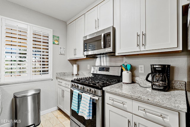 kitchen featuring white cabinetry, light tile patterned floors, light stone countertops, and appliances with stainless steel finishes