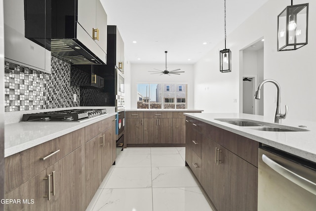 kitchen with pendant lighting, sink, backsplash, stainless steel appliances, and light stone countertops