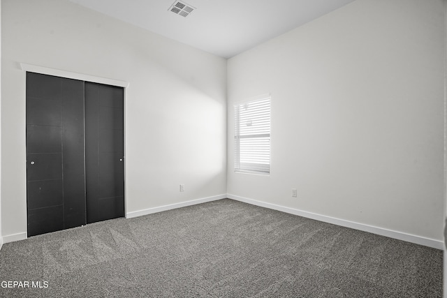 unfurnished bedroom featuring dark colored carpet and a closet