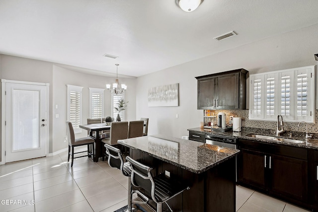 kitchen featuring sink, light tile patterned floors, dark stone countertops, a chandelier, and a kitchen island