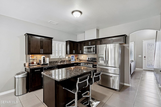 7828 Enchanted View Dr, El Paso, TX 79911 - kitchen with stainless steel appliances, light tile patterned floors, dark stone counters, a kitchen island, and backsplash
