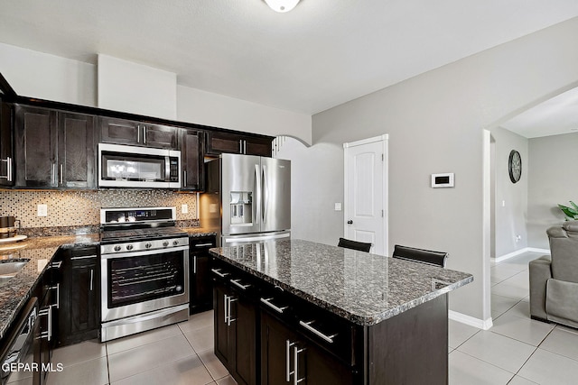 7828 Enchanted View Dr, El Paso, TX 79911 - kitchen with appliances with stainless steel finishes, light tile patterned floors, arched walkways, and dark stone countertops