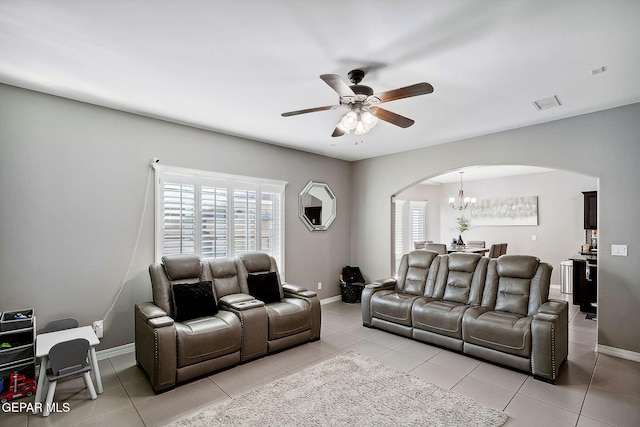 tiled living room featuring ceiling fan with notable chandelier