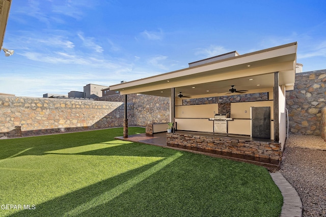 view of yard with ceiling fan and exterior kitchen