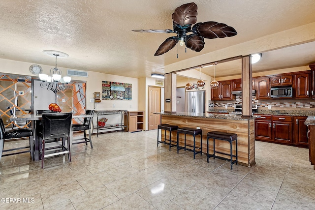 kitchen featuring a breakfast bar, tasteful backsplash, decorative light fixtures, a kitchen island, and stainless steel refrigerator