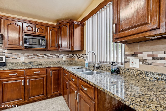 kitchen featuring stone counters, backsplash, stainless steel appliances, and sink